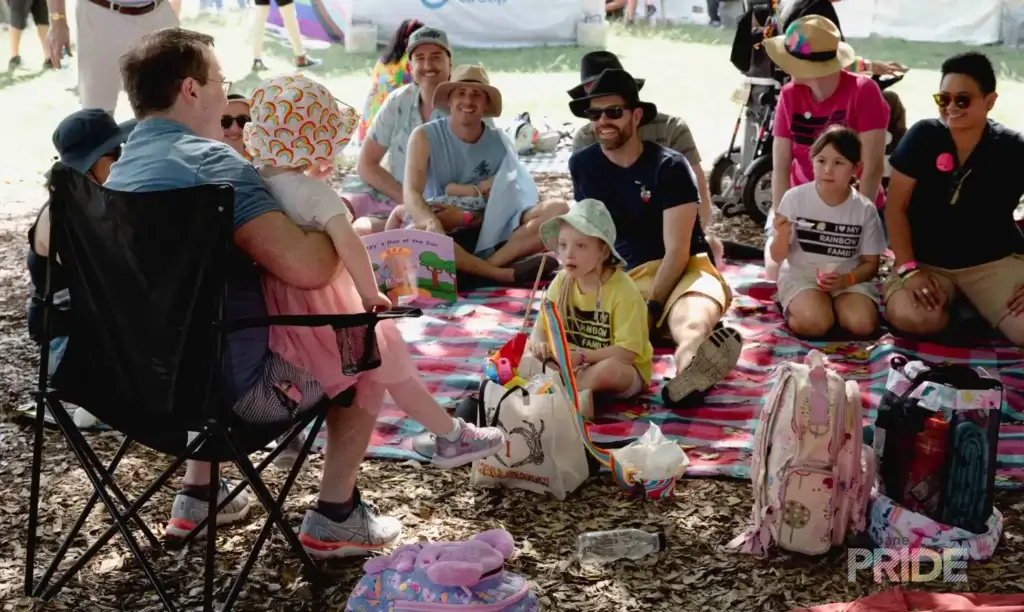 Families and friends spread across picnic rugs and camp chairs on the grass at Fair Day, several children among them.